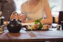 Крупный план суши на столе с парой обедающих на заднем плане в ресторане — стоковое фото