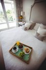 Breakfast tray on bed in bedroom at home — Stock Photo
