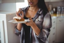 Seção média de mulher tomando café da manhã na cozinha em casa — Fotografia de Stock