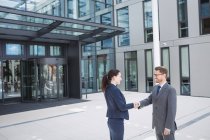 Businessman shaking hands with colleague outside office building — Stock Photo