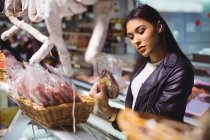 Donna che seleziona salsiccia al bancone della carne al supermercato — Foto stock