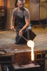 Стеклодув, работающий над расплавленным стеклом на стекольном заводе — стоковое фото