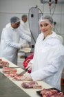 Ritratto di macelleria femminile che taglia carne in fabbrica — Foto stock