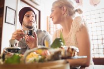 Casal interagindo uns com os outros enquanto toma chá no restaurante — Fotografia de Stock