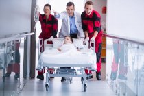 Médecins poussant lit civière d'urgence dans le couloir à l'hôpital — Photo de stock