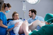Médico examinando mulher grávida durante o parto na sala de cirurgia — Fotografia de Stock