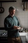Mann benutzt Handy beim Frühstück in der heimischen Küche — Stockfoto