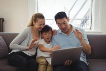 Семья, имеющая видеочат на ноутбуке в гостиной дома — стоковое фото