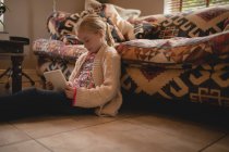 Fille assise sur le sol et en utilisant une tablette numérique dans le salon à la maison — Photo de stock