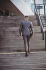 Rückansicht eines Geschäftsmannes mit Tagebuch beim Treppensteigen im Büro — Stockfoto