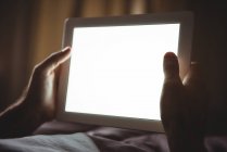 Primer plano de las manos masculinas utilizando tableta digital en el dormitorio en casa - foto de stock