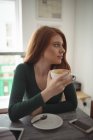 Молодая женщина пьет кофе в ресторане — стоковое фото