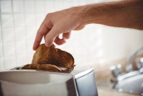 Gros plan sur l'homme grillant du pain dans la cuisine à la maison — Photo de stock