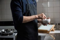 Mid-section of man using pestle and mortar in kitchen at home — Stock Photo