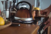 Preparing tea in teakettle on stove in kitchen — Stock Photo