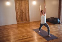 Mulher adulta média praticando ioga guerreiro posar no estúdio de fitness — Fotografia de Stock