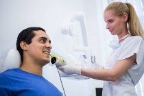 Dentista tomando radiografía de dientes de paciente masculino en clínica - foto de stock
