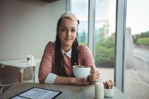 Portrait de femme souriante prenant une tasse de café dans un café — Photo de stock