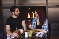 Друзья общаются во время еды в баре — стоковое фото