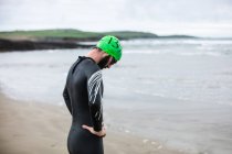 Müder Athlet bückt sich am Strand, um Luft zu holen — Stockfoto