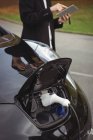 Voiture chargée avec chargeur de voiture électrique à la station de recharge du véhicule électrique — Photo de stock