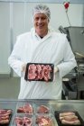 Retrato de açougueiro segurando bandeja de carne na fábrica de carne — Fotografia de Stock