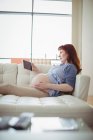 Donna incinta che guarda una sonografia sul tavolo digitale in soggiorno — Foto stock