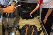 Personal femenino que controla el equipaje de los pasajeros en la cinta transportadora en el aeropuerto - foto de stock