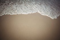 Primer plano de las olas que vienen hacia la playa de arena - foto de stock
