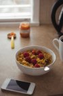 Cereais café da manhã com xícara de café e telefone celular na bancada da cozinha em casa — Fotografia de Stock