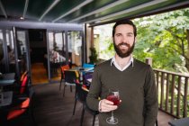 Ritratto di uomo sorridente che tiene un bicchiere di vino in un bar — Foto stock