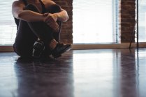 Обрезанный вид женщины, отдыхающей на полу в танцевальной студии — стоковое фото