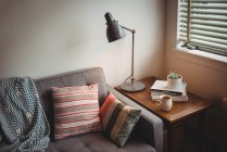 Sofá e lâmpada de mesa na sala de estar em casa — Fotografia de Stock