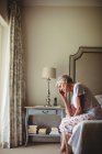Worried senior woman with head in hands sitting in bed room — Stock Photo