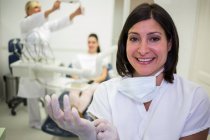Retrato del dentista sonriente con guantes quirúrgicos - foto de stock