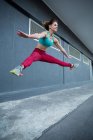 Mujer saltando mientras practica parkour en la calle - foto de stock