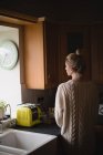 Vue arrière de femme réfléchie dans la cuisine à la maison — Photo de stock