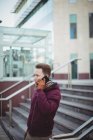 Young man talking on mobile phone on street in city — Stock Photo