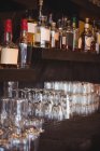 Close-up de garrafas e copos dispostos em prateleiras em um bar — Fotografia de Stock