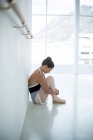 Traurige Ballerina sitzt im Ballettstudio auf dem Boden — Stockfoto
