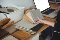 Section médiane du dirigeant d'entreprise tenant des dalles de pierre et utilisant un ordinateur portable dans le bureau — Photo de stock