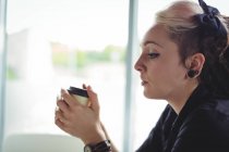 Женщина с одноразовой чашкой кофе в кафе — стоковое фото