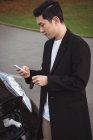 Mann benutzt Handy beim Laden von Elektroauto auf Straße — Stockfoto