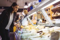 Mulher olhando para exibição de queijo no supermercado — Fotografia de Stock