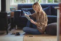 Mulher bonita ler livro enquanto toma chá na sala de estar em casa — Fotografia de Stock