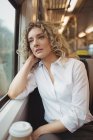 Thoughtful businesswoman looking through window while travelling — Stock Photo