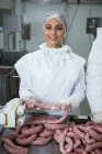 Female butcher processing sausages at meat factory — Stock Photo