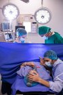 Equipo de médicos examinando a la mujer embarazada durante el parto en la sala de operaciones - foto de stock