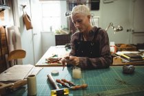 Attentive craftswoman preparing leather belt in workshop — Stock Photo