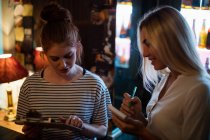 Kellnerin diskutiert mit Frau in der Bar über das Menü — Stockfoto